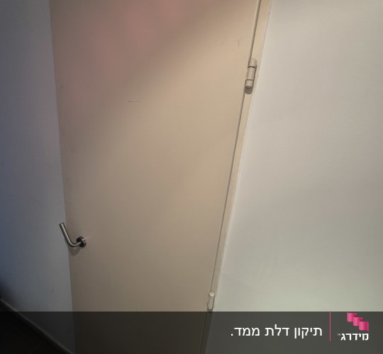 דלת עם ידית מתכת על קיר לבן
